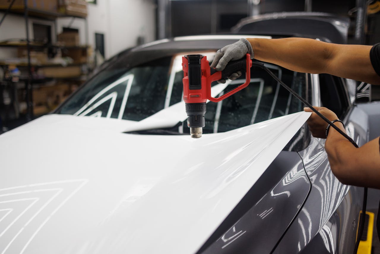 gallery-01 Worker applying a car wrap using a heat gun for precise adhesion.
