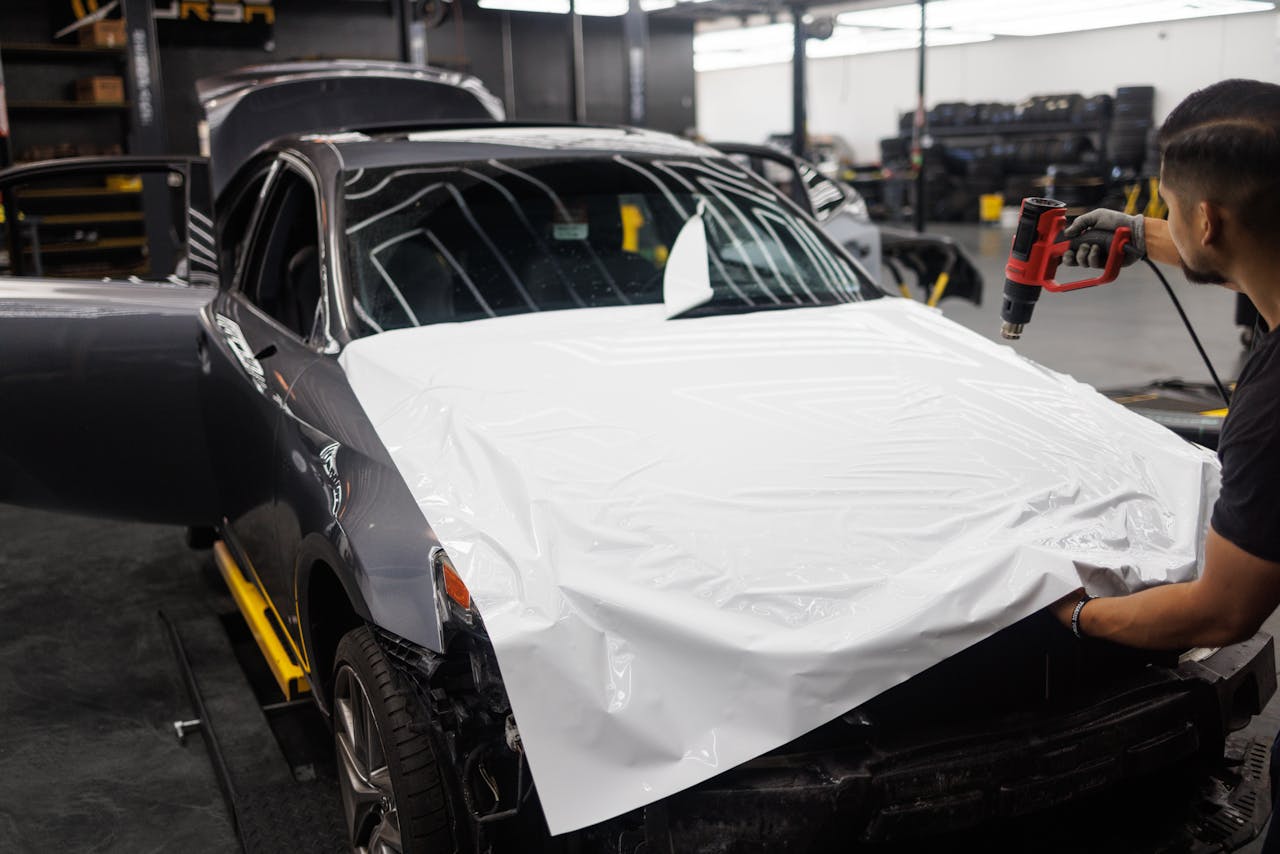 gallery-04 Car being wrapped with white vinyl in an auto workshop by a skilled mechanic.